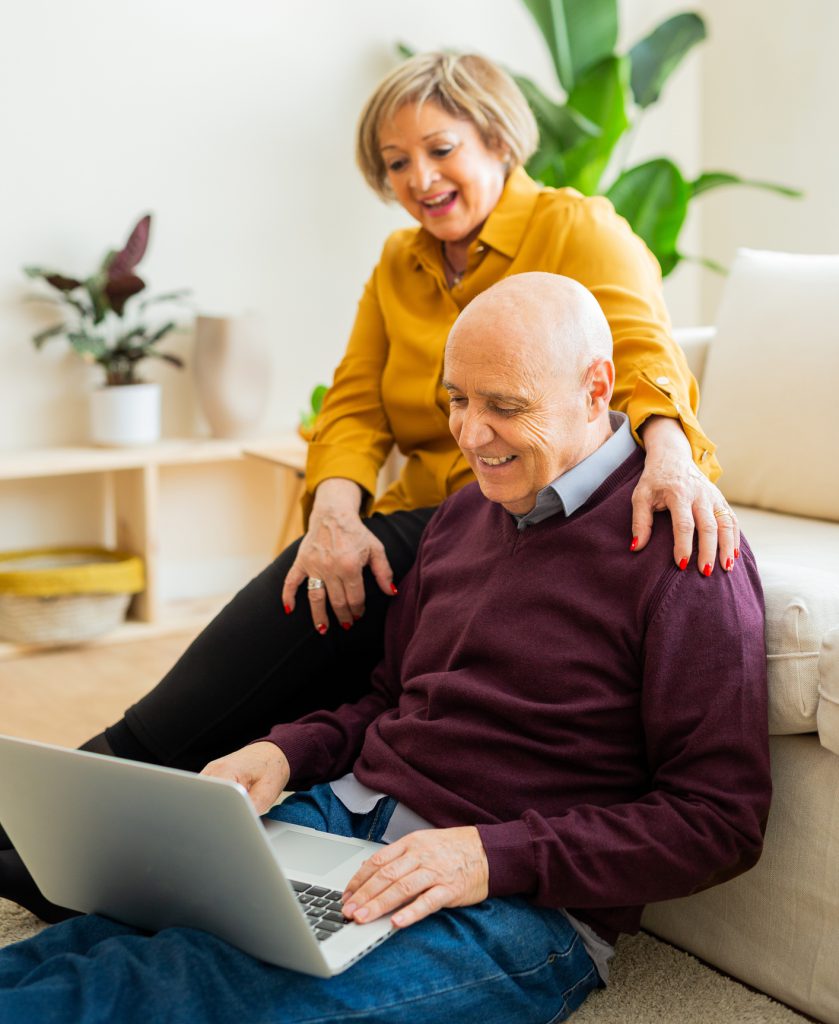 Casal de idosos navegando na internet na sala de estar de casa.